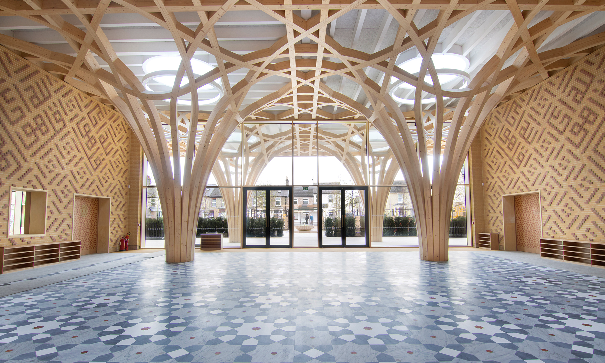 The tree-like wooden supporting structure dominates the entrance area of the Cambridge Mosque. The floor is designed as a grey/blue tiled mosaic while the walls are of two-coloured clinker brick with oriental motifs.